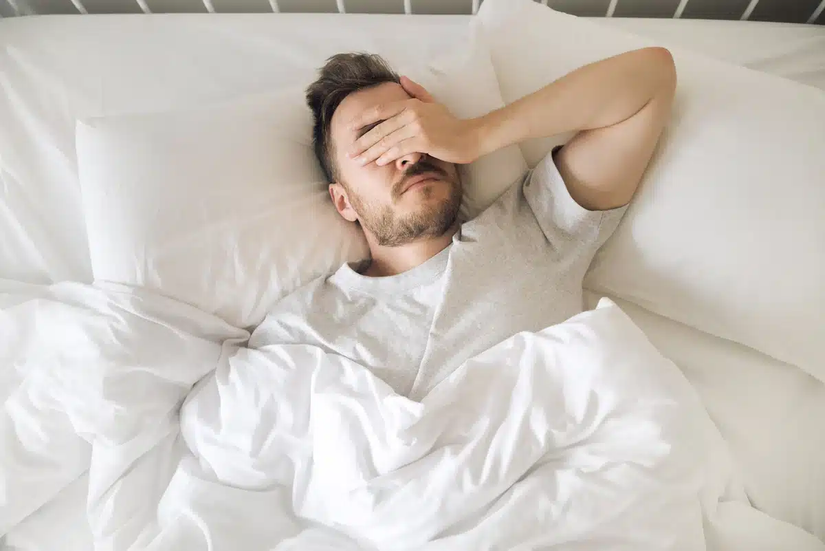 Blog 2 Man in bed, looking distressed and tired.